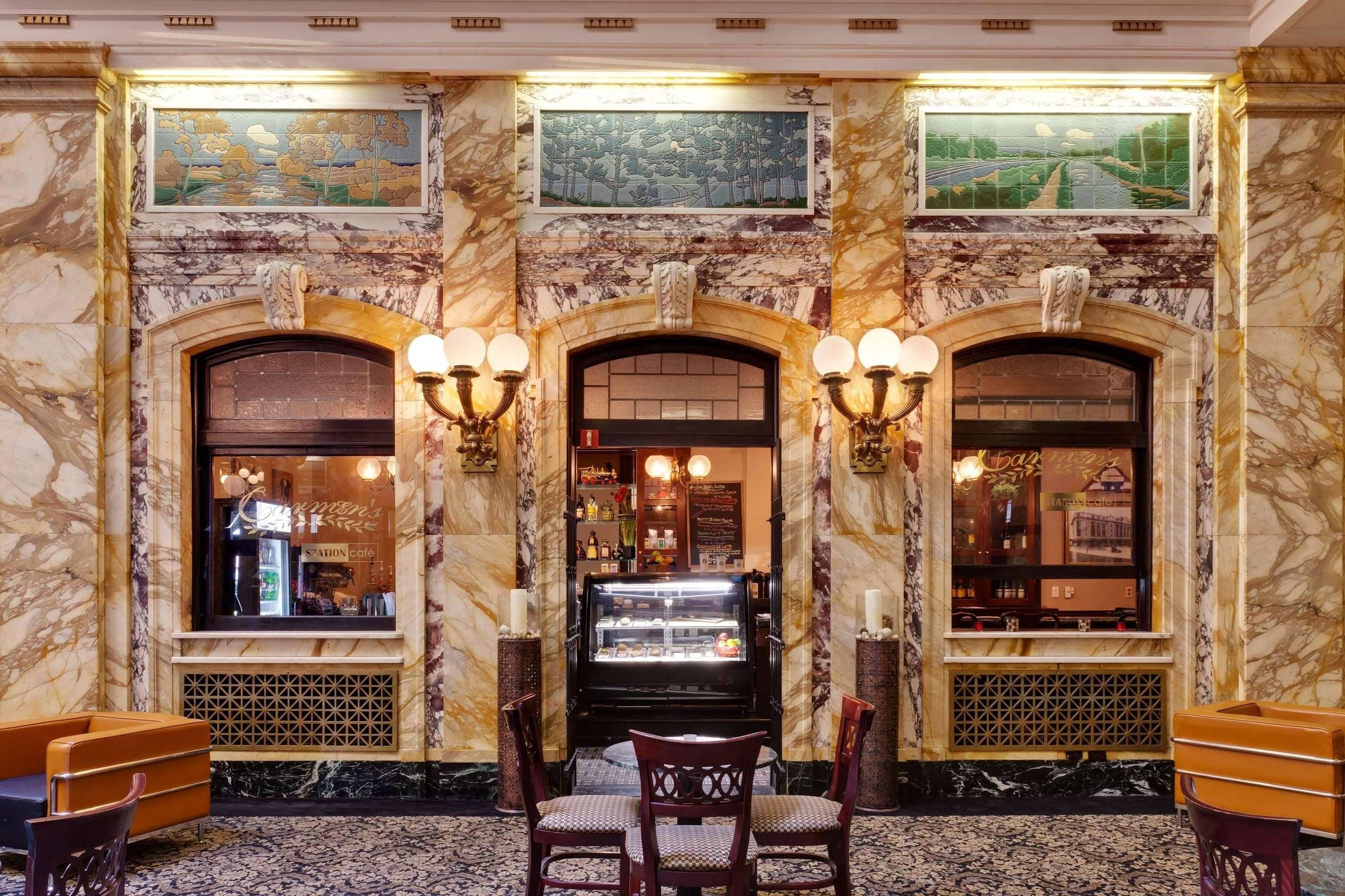 A marble-floored lobby with a central seating area, two side counters, and a decorative fireplace.