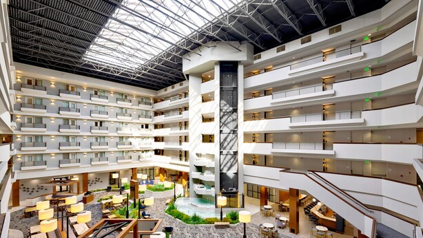 A multi-level hotel atrium with a central water feature, multiple balconies, and various seating areas. - DoubleTree by Hilton Davenport (Davenport)