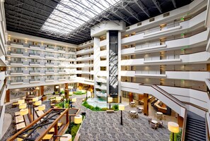 A multi-level hotel atrium with a central water feature, multiple balconies, and various seating areas. - DoubleTree by Hilton Davenport (Davenport)