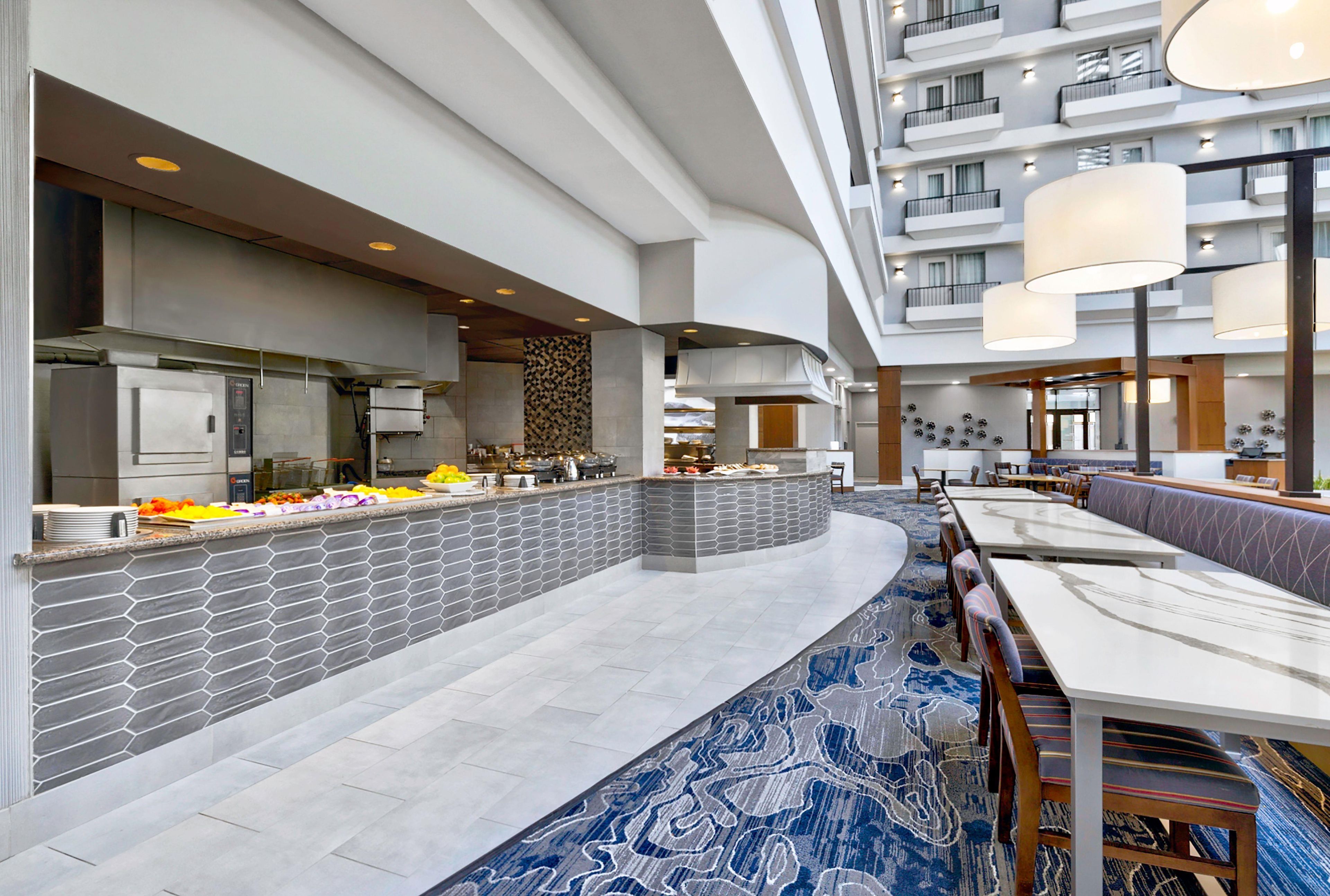 Eine moderne Hotelhalle mit einem zentralen Buffet, einer Sitzecke und einem großzügigen Atrium.