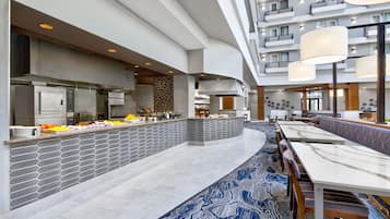 Eine moderne Hotelhalle mit einem zentralen Buffet, einer Sitzecke und einem großzügigen Atrium.