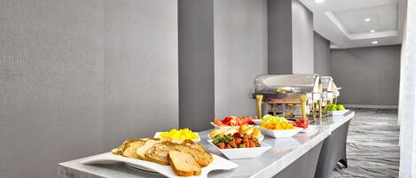 A buffet setup with various food items and a self-service beverage station in a modern hotel setting.