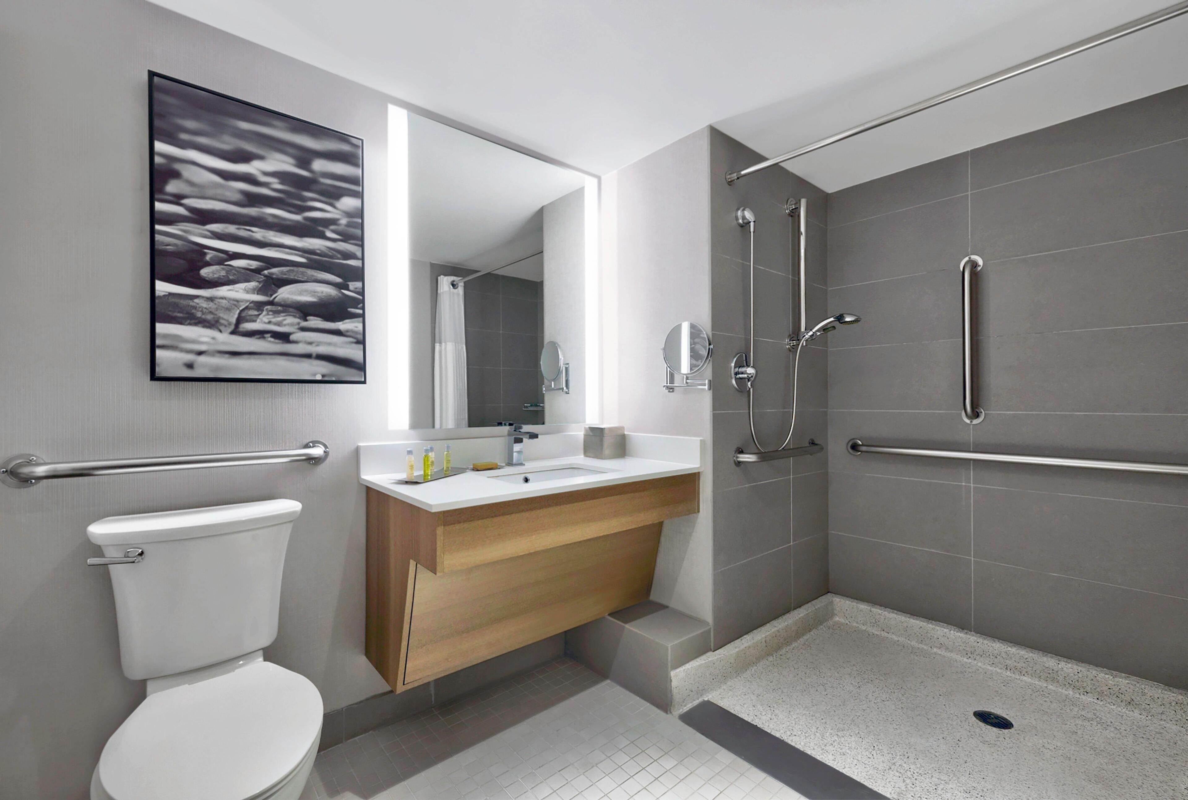 A modern bathroom with a toilet, sink, shower, and a mirror.