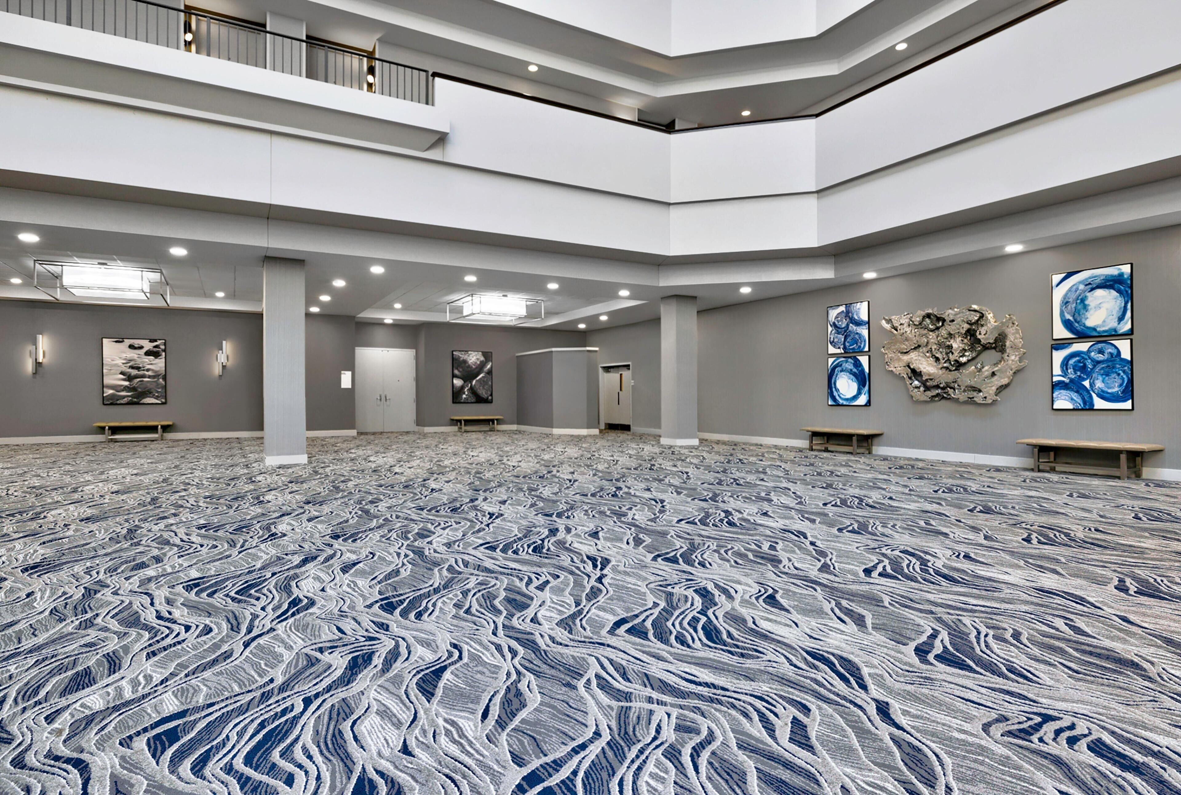 Un vaste atrium à plusieurs niveaux, agrémenté d’un tapis à motifs, d’œuvres d’art sur les murs et d’une mezzanine.