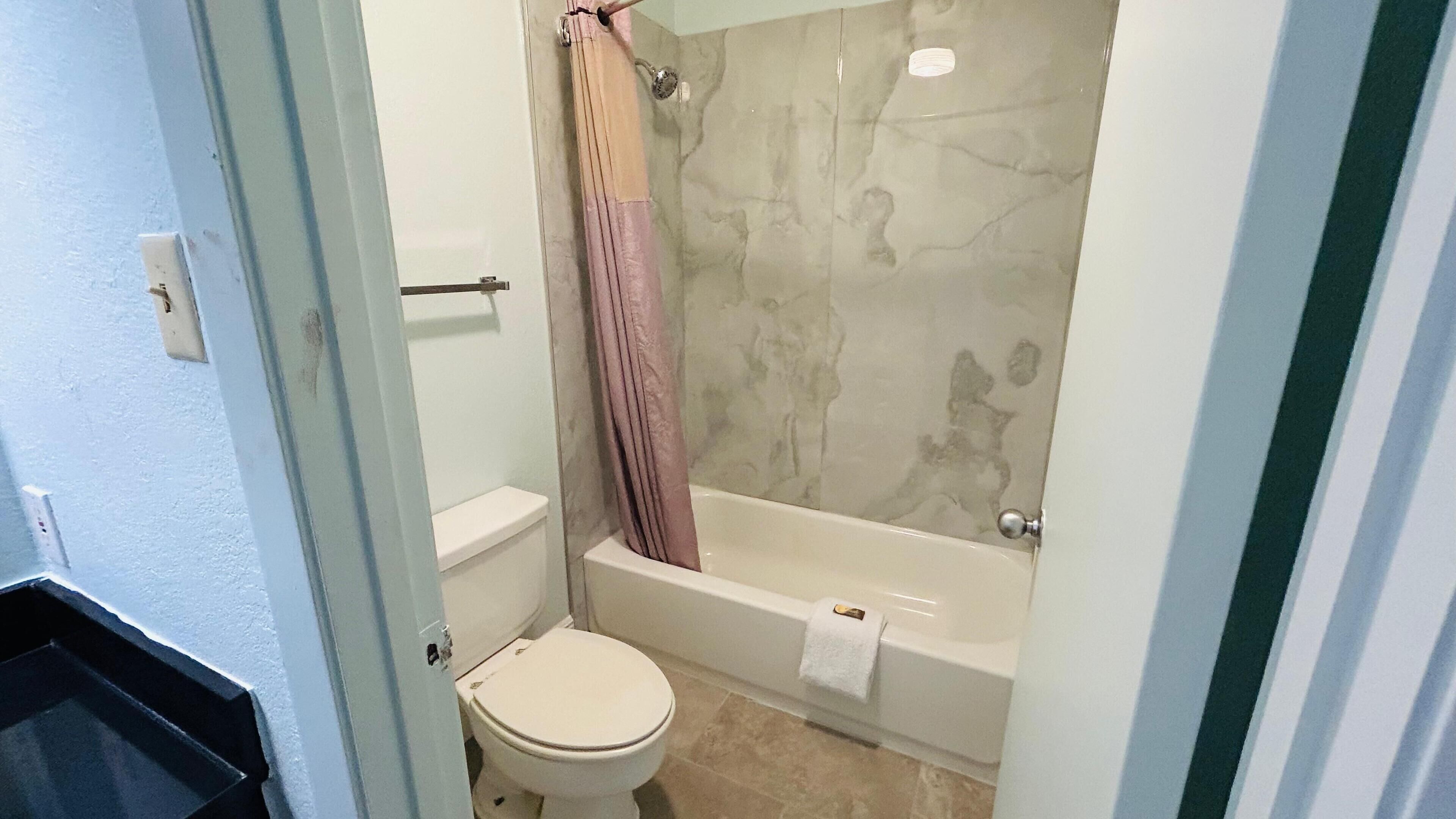A bathroom with a toilet, a shower with a glass door, and a bathtub.