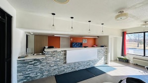 A reception area with a stone counter, a clock, and a window with a view of the outside. - Super 7 Inn Tupelo (Tupelo)