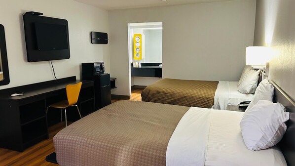 A hotel room with two beds, a desk with a chair, a television, and a mirror.