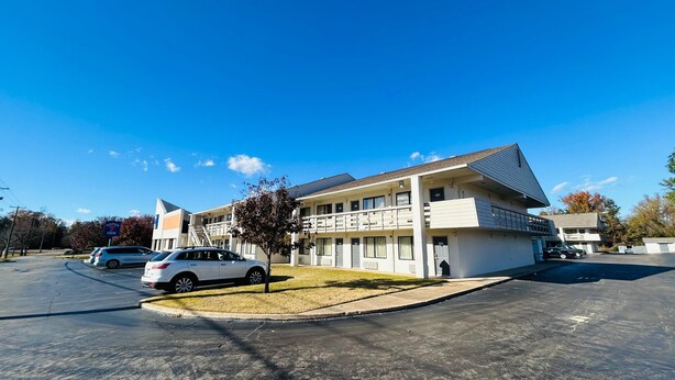 A Super 7 Inn with a two-story building, a parking lot, and a clear blue sky. - Super 7 Inn Tupelo (Tupelo)
