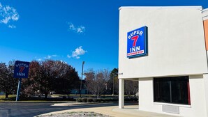 A Super 7 Inn building with a clear blue sky and trees in the background.