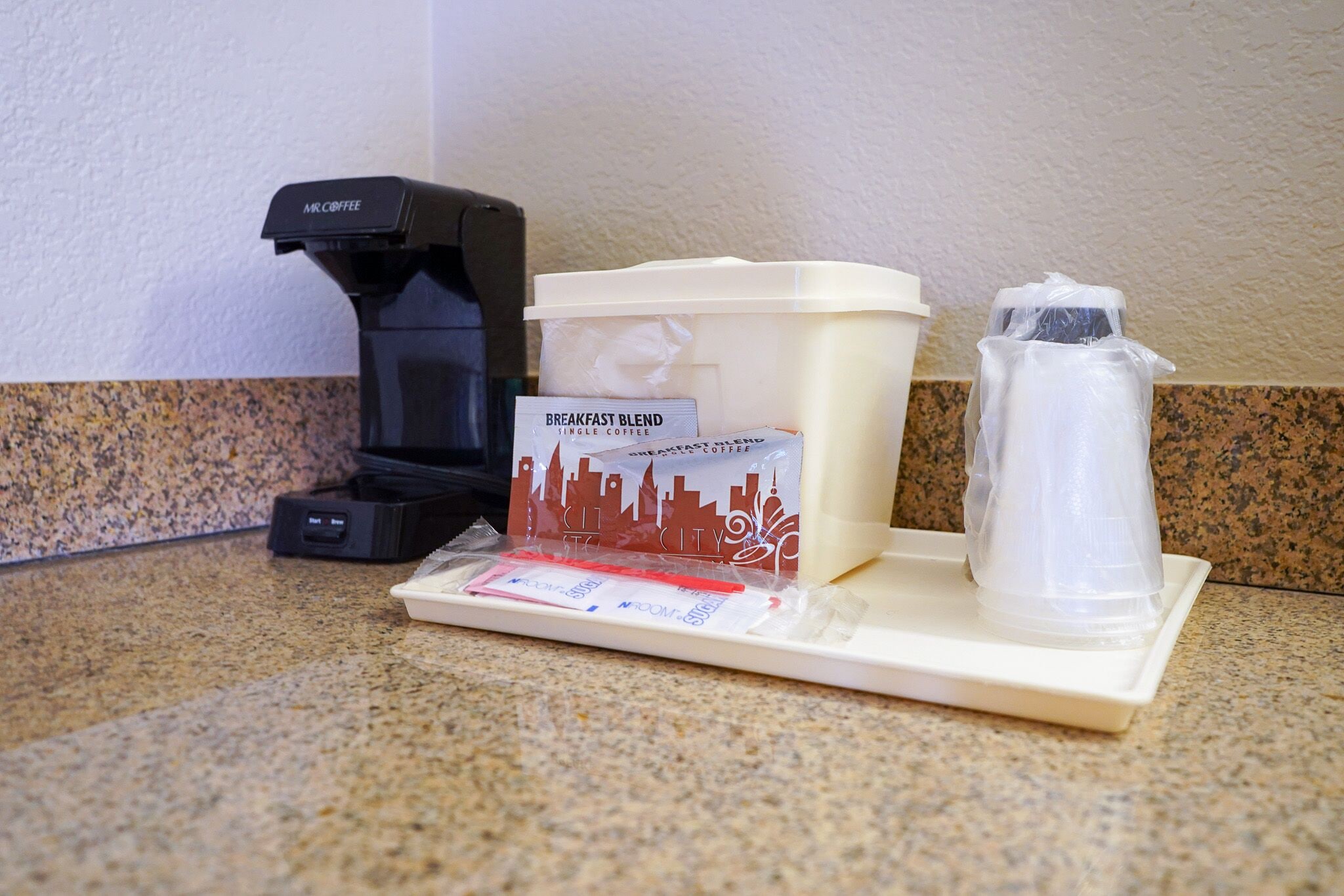 A coffee maker, a coffee pod dispenser, a water pitcher, and a coffee cup on a countertop.