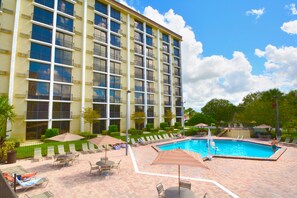 Una piscina al aire libre, sombrillas, sillones reclinables de piscina