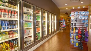 A corridor with refrigerated beverage dispensers on one side and a display of umbrellas on the other. - Rosen Inn, closest to Universal (Orlando)