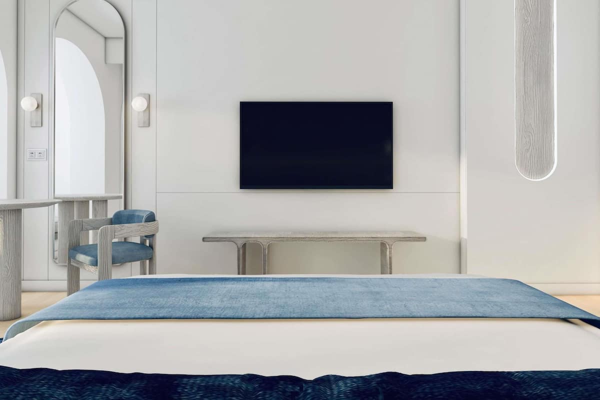 A modern bedroom with a bed, a TV mounted on the wall, a desk, and a chair.