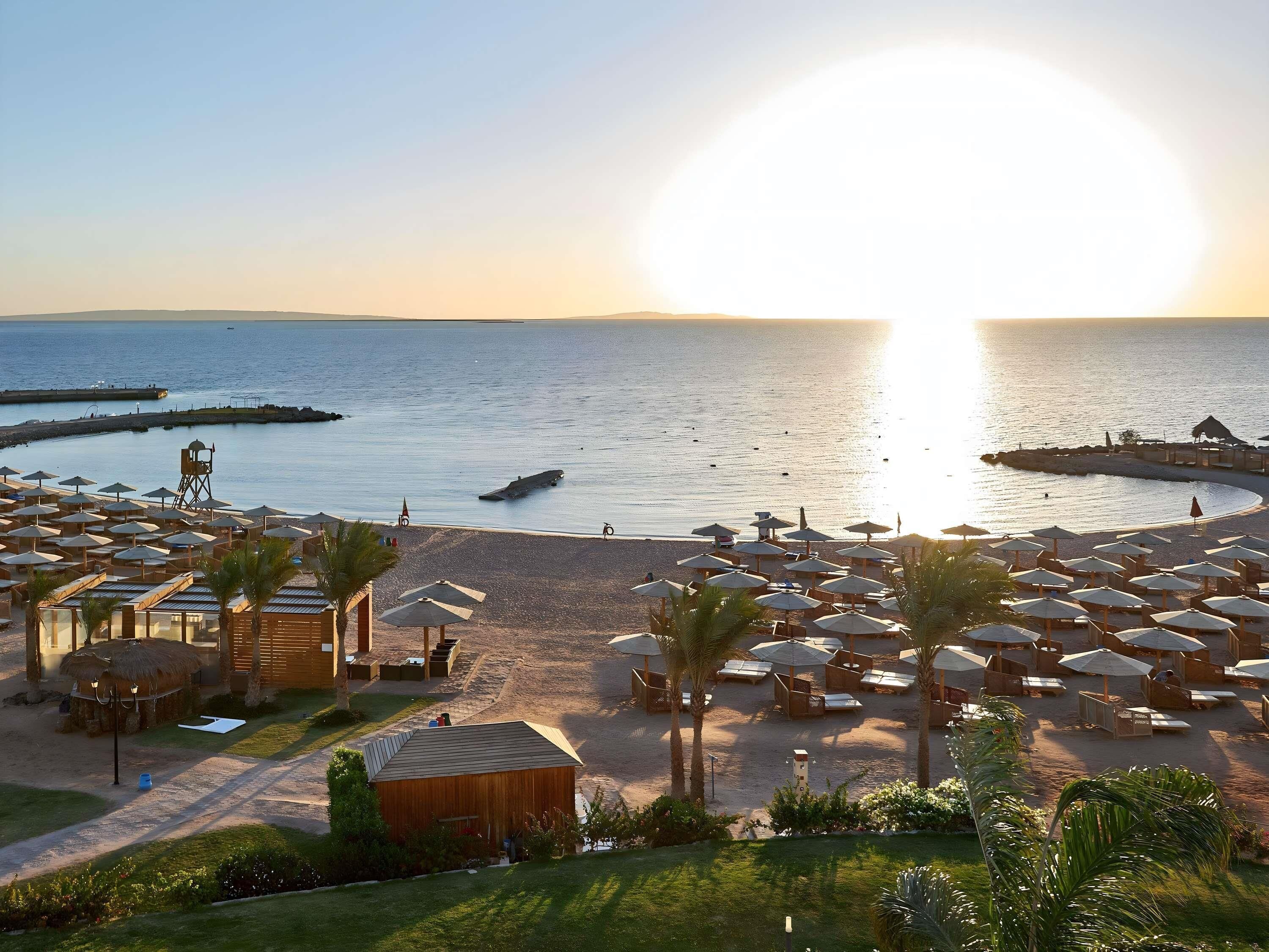 Un complexe hôtelier de bord de mer équipé de parasols, de chaises longues et d’une tour de surveillance pour les sauveteurs.