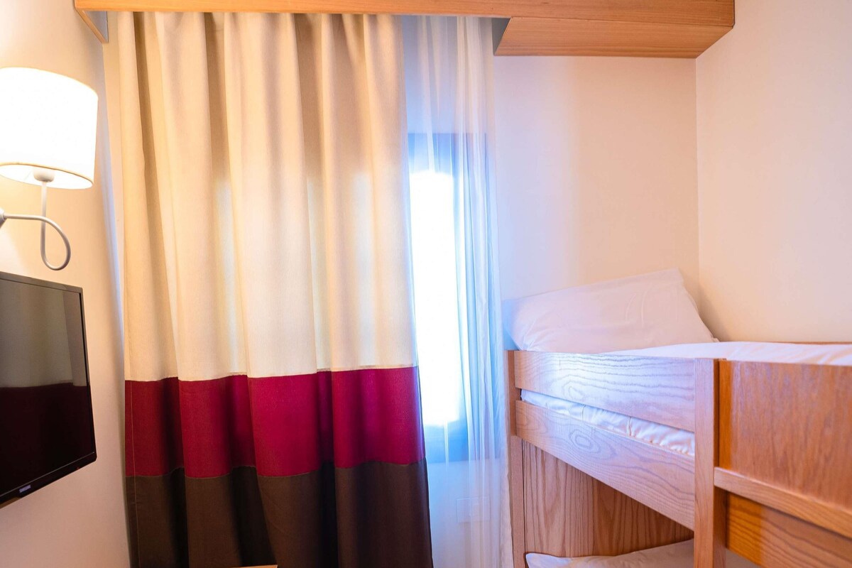 A hotel room with a bed, a TV, and a curtain.