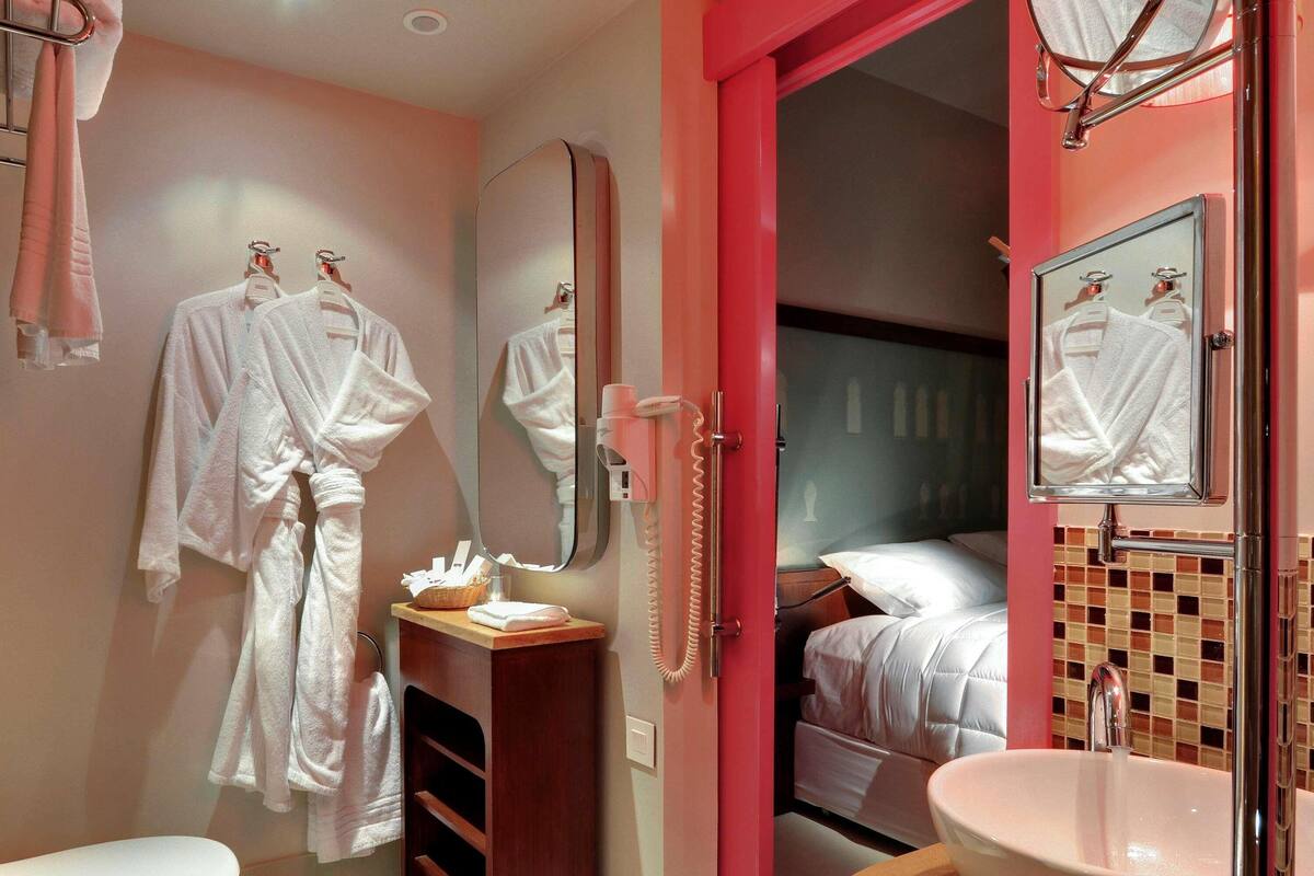 A bathroom with a toilet, a sink, a mirror, and a shower area.