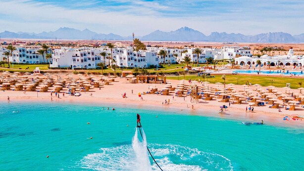 A coastal resort with a clear turquoise sea, a water jet feature, and a backdrop of mountains. - Mercure Hurghada Hotel (Hurghada)