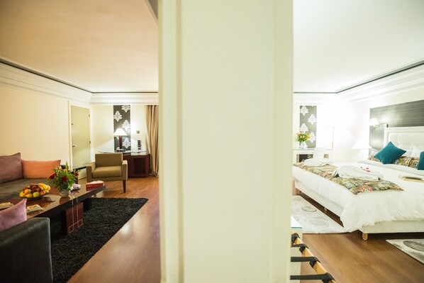 Una habitación de hotel moderna con sofá, sillón y cama bien tendida.