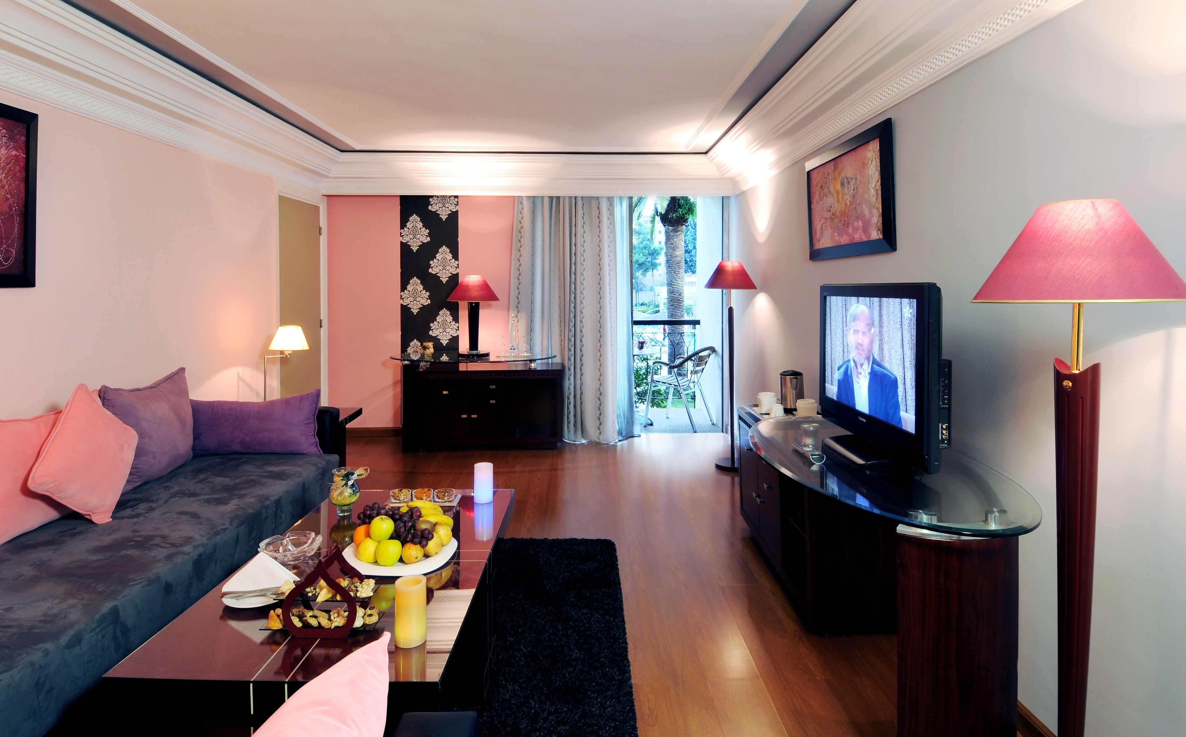 Una sala de estar moderna con sofá, mesa de centro, televisor y vista al balcón.