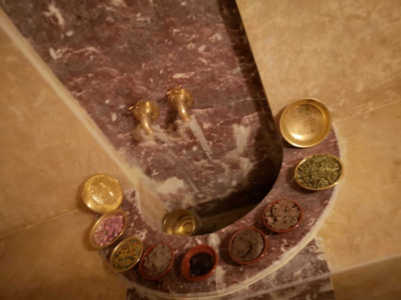 Un sòl de marbre amb un arc reencordat que conté diversos recipients ceràmics petits i rodons, amb continguts de diferents colors.