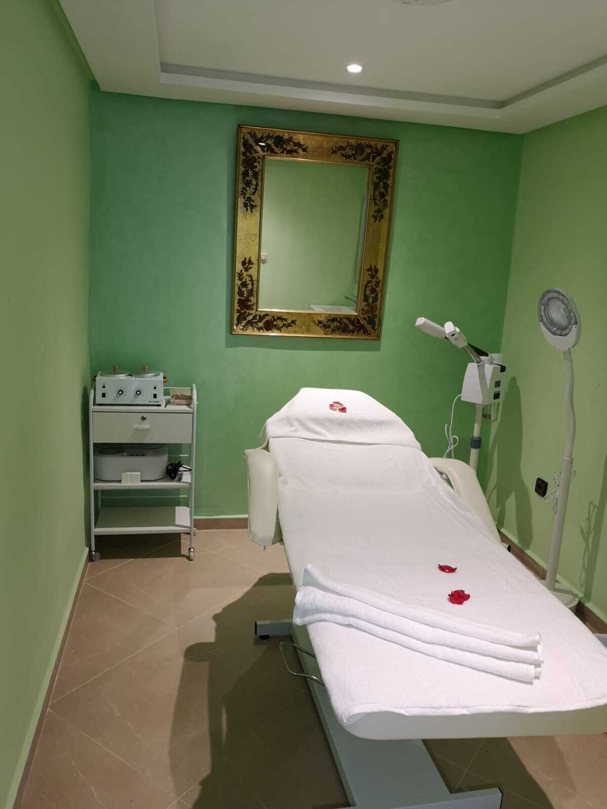 A medical examination room with a bed, a cabinet with medical equipment, and a mirror on the wall.