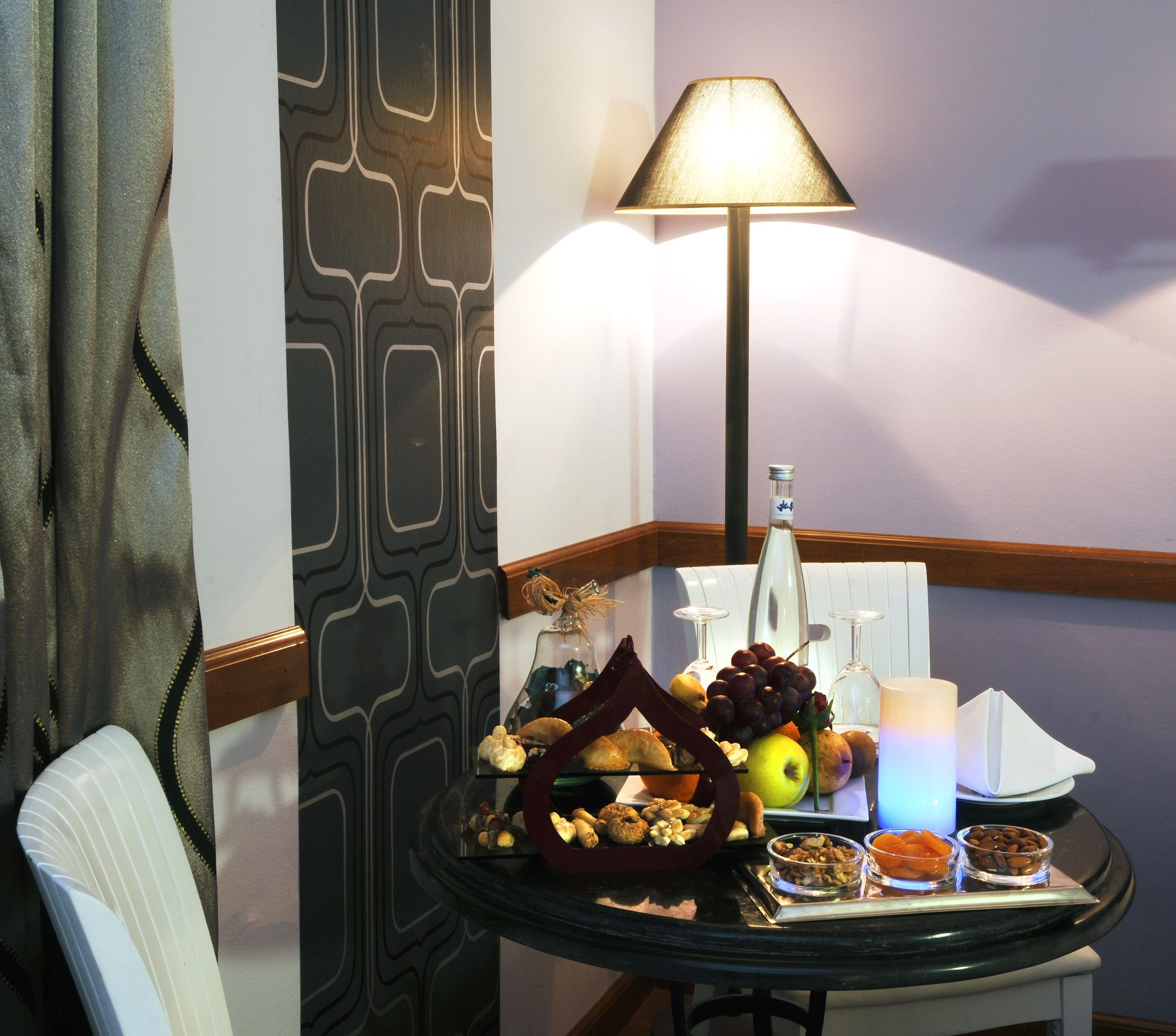 A dining table with a variety of food items, a bottle, and a lamp.