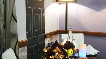A dining table with a variety of food items, a bottle, and a lamp.