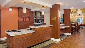Ein Hotel-Empfangsbereich mit einem Holzbüro, einer Bar und einer Sitzecke.