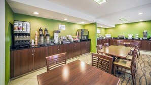 A modern kitchen with a coffee station, dining area, and green walls.