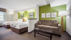 A hotel room with two beds, a sofa, a coffee table, and artwork on the walls.