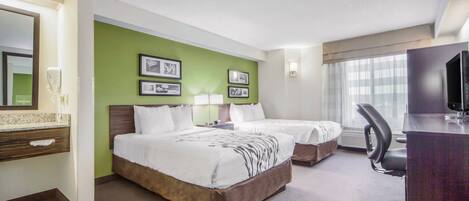 A hotel room with two beds, a desk with a chair, a TV, and framed pictures on the wall.