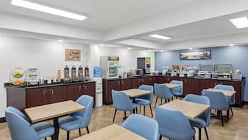 A modern cafe with multiple seating areas, a coffee station, and a refrigerator.