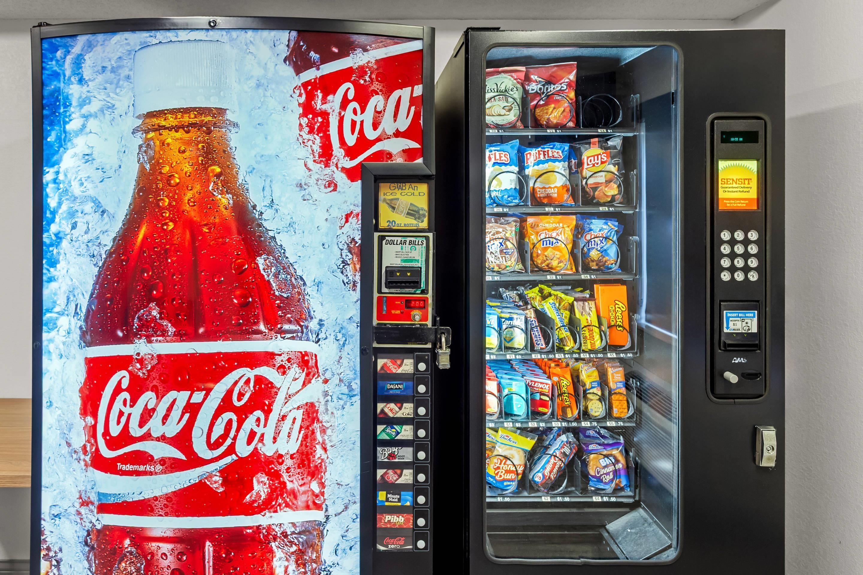 A vending machine with a Coca-Cola advertisement and a selection of snacks.