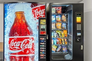 Máquina automática de vendas com anúncio de Coca-Cola e variedade de lanches.