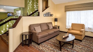A living room with a sofa, armchair, coffee table, and a patterned carpet. - Sleep Inn Charleston North (Charleston)