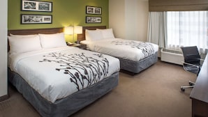 A hotel room with two beds, a desk, a chair, and a large window with curtains. - Sleep Inn Charleston North (Charleston)