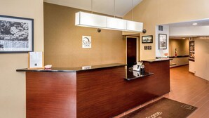A reception desk with a wooden finish, a 'Sleep Inn' sign, a welcome mat, and a framed picture on the wall. - Sleep Inn Charleston North (Charleston)