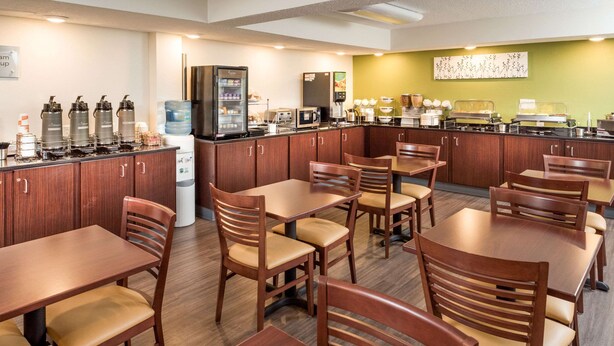 A restaurant with wooden tables and chairs, a refrigerator, a microwave, and a coffee station. - Sleep Inn Charleston North (Charleston)