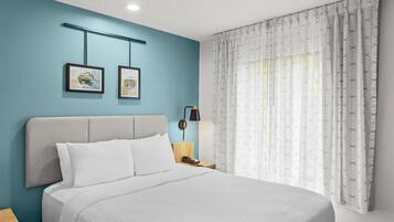 Habitación de hotel con cama, mesita de noche, lámpara y dos cuadros en la pared.