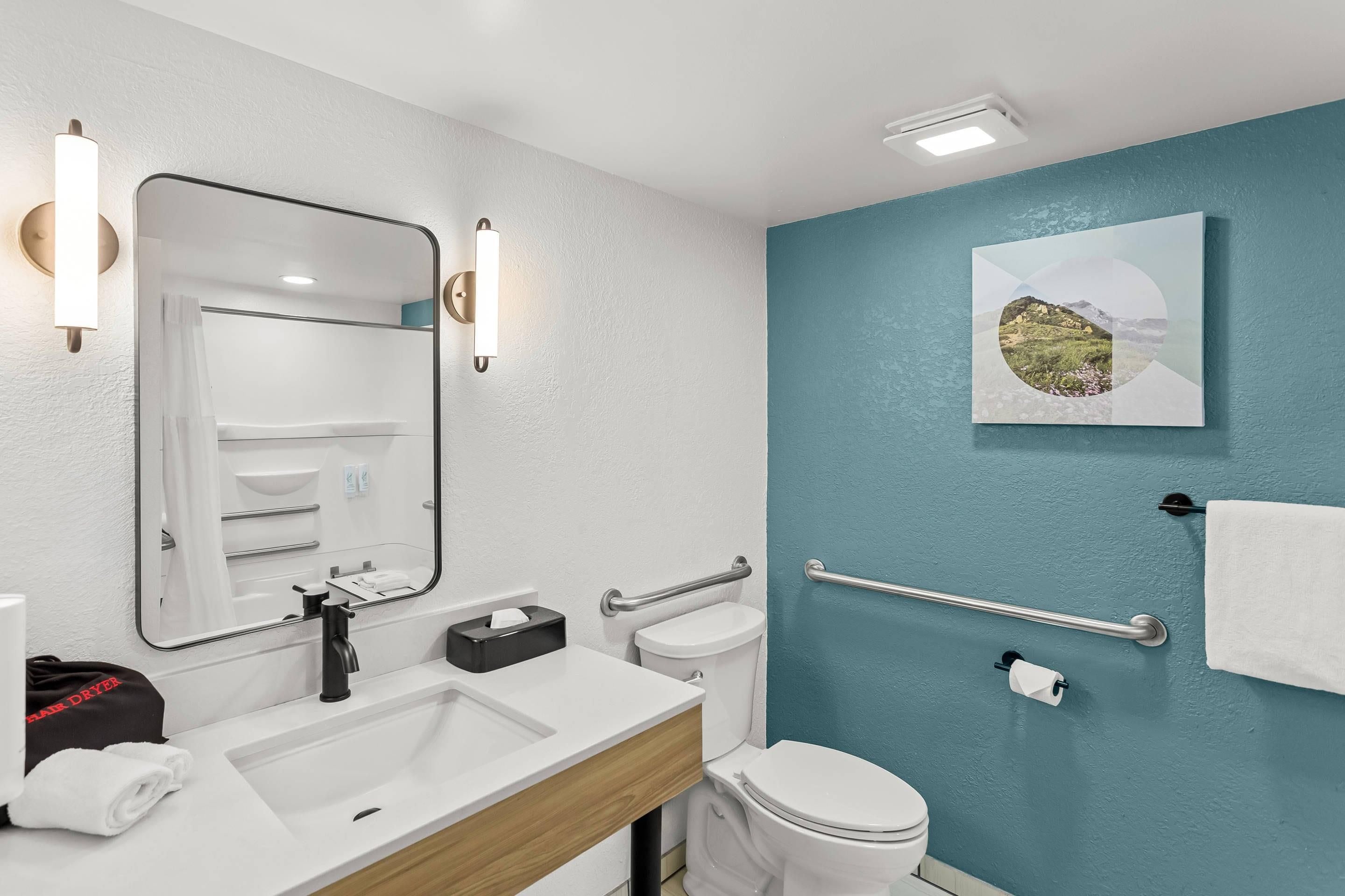A modern bathroom with a white sink, a mirror, a toilet, and a towel rack.