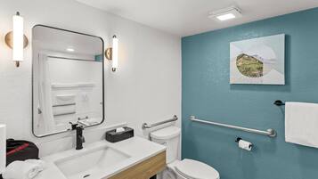 A modern bathroom with a white sink, a mirror, a toilet, and a towel rack.