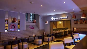 Ein Restaurant mit modernem Ambiente, das eine Bar, Sitzgelegenheiten und einen Einblick in den Essbereich bietet.