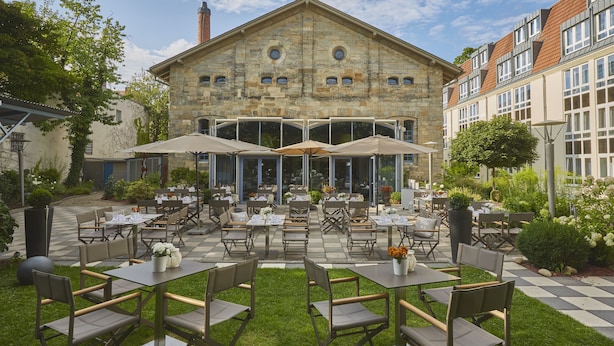 A courtyard with outdoor seating, a stone building, and a checkered floor.