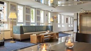 A modern hotel lobby with a sofa, coffee table, and a dining table with candles.