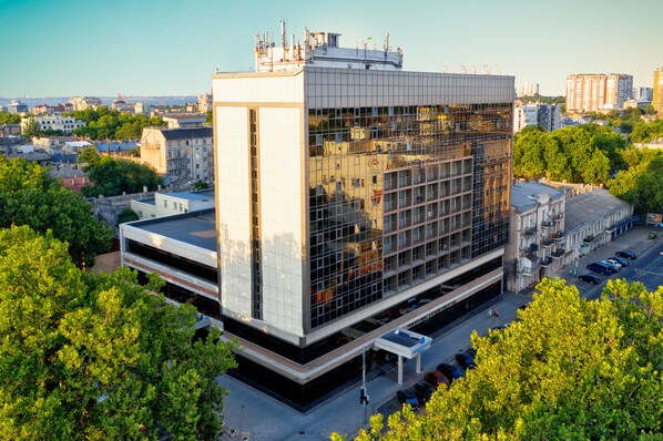 A modern building with a glass facade, surrounded by trees and other buildings. - Black Sea Central (Odessa)