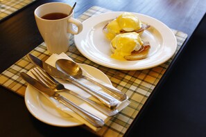 A breakfast setting with eggs benedict on a plate, a cup of coffee, and cutlery on a placemat. - The Victoria Hotel Manchester by Compass Hospitality (Oldham)