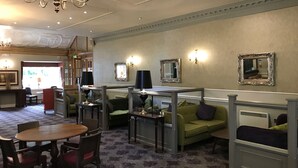 A spacious room with a dining table and chairs, a green sofa, and a chandelier. - The Victoria Hotel Manchester by Compass Hospitality (Oldham)