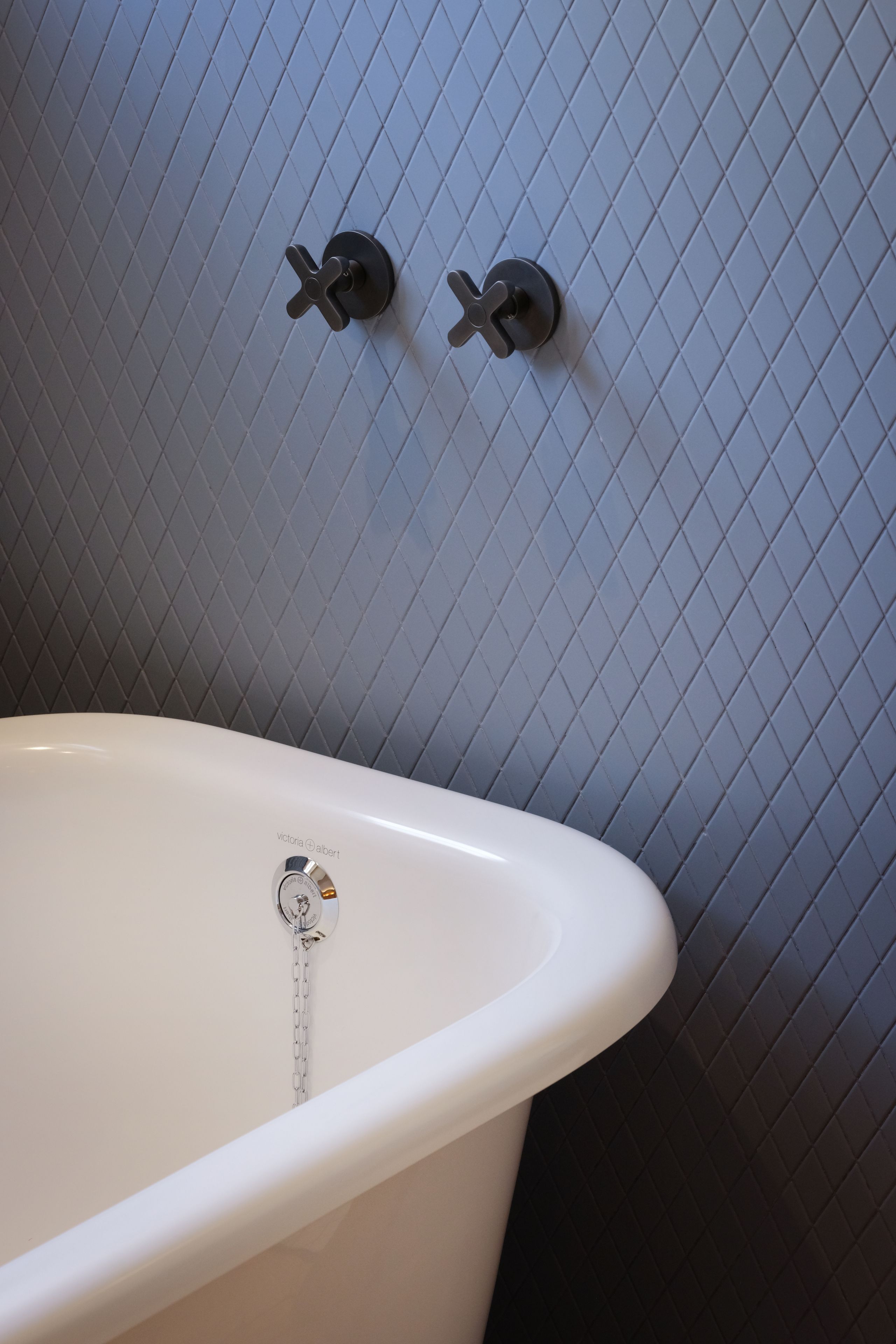 Una bañera con un grifo y ducha, frente a una pared de azulejos.