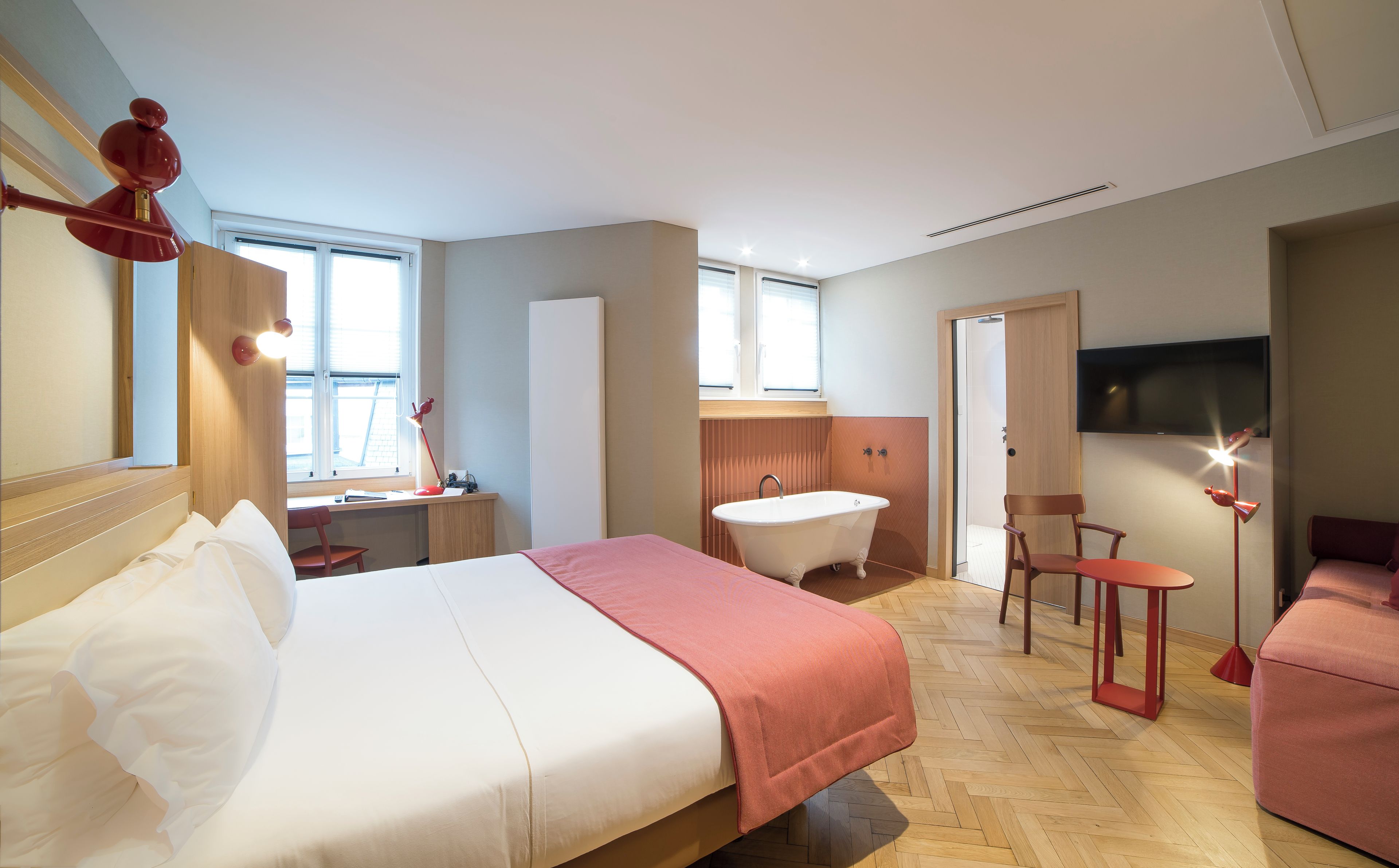 Ein Hotelzimmer mit Bett, Schreibtisch, Stuhl, Badewanne und Fernseher.