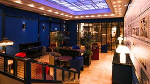 A lobby with a piano, seating areas, a staircase, and a glass ceiling. - Hotel Hannong (Strasbourg)